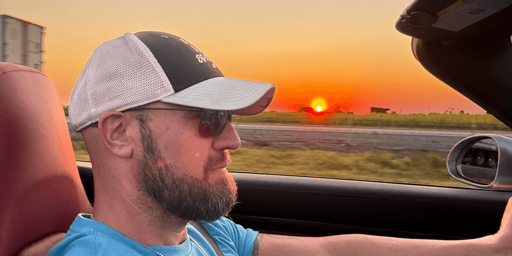 profile of man's head while driving with Oklahoma sunset and silhouettes of cattle